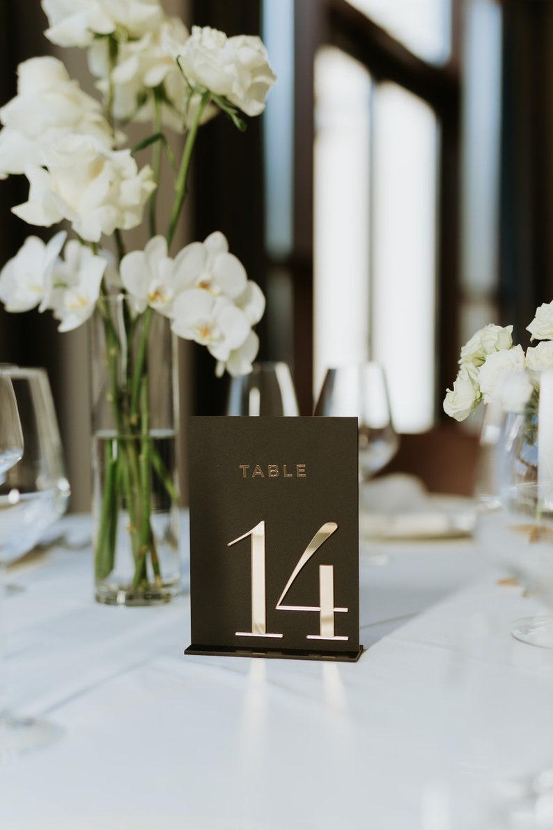 May include: A black table number card with gold lettering. The card reads "TABLE 14".