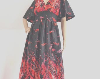 May include: A floor-length black dress featuring a vibrant red and pink abstract brushstroke pattern. The garment has a V-neckline, a fitted waist, and wide, flared flutter sleeves that extend to the elbows, creating a flowing silhouette.