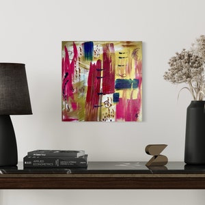 Può includere: Dipinto astratto con pennellate audaci di rosso, giallo e blu su una tela. Il dipinto è incorniciato e appeso a una parete bianca sopra un tavolo console di colore marrone scuro.