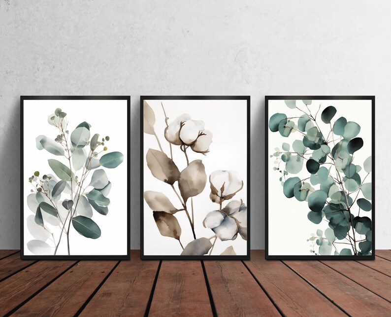 May include: Set of three framed watercolor prints featuring botanical illustrations of eucalyptus leaves and cotton blossoms. The prints are in shades of green, brown, and white.