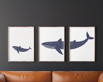 May include: Three framed prints of whale silhouettes in navy blue on white paper. The whales are made up of repeating lines and are different sizes. The prints are hanging on a dark gray wall.