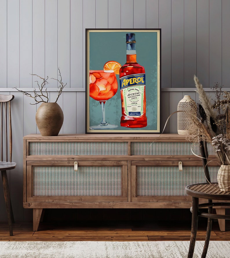 K&ouml;nnte beinhalten: Ein Vintage-Poster mit einer Flasche Aperol, einem italienischen Lik&ouml;r, und einem Glas Aperol Spritz. Das Poster hat einen blauen Hintergrund mit einem wei&szlig;en Rand und den Text "Aperol Aperitivo 1919" in wei&szlig;.