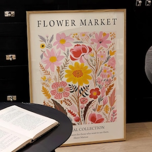 May include: A framed print with a floral design featuring pink, yellow, red, and orange flowers. The print has the text "FLOWER MARKET" and "AL COLLECTION" with a quote by Henri Matisse.