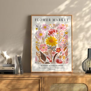 May include: A framed print with a floral design featuring pink, yellow, and red flowers. The print has the text "FLOWER MARKET" and "BOTANICAL COLLECTION" with a quote by Henri Matisse.