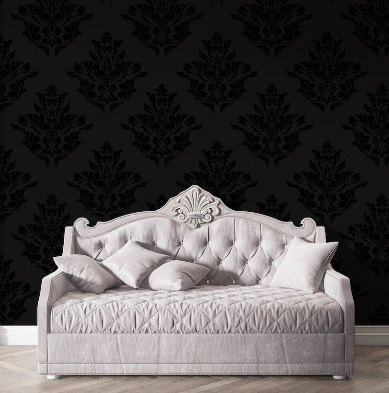 May include: A white tufted daybed with a black damask patterned wallpaper behind it. The daybed has a tufted headboard and a quilted mattress.