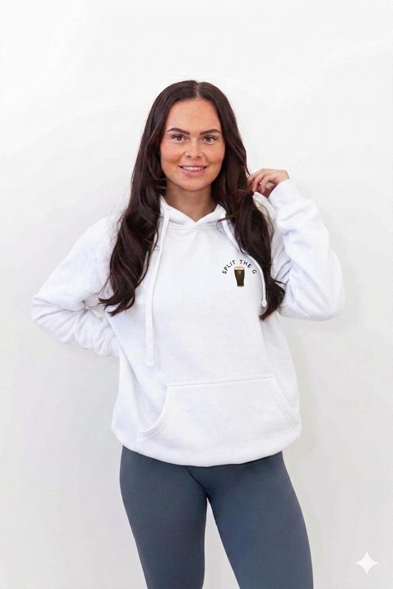 May include: White hoodie with a front pocket and drawstring. The hoodie has the text "SPLIT THE G" with a graphic of a pint of stout. The model is wearing gray leggings.