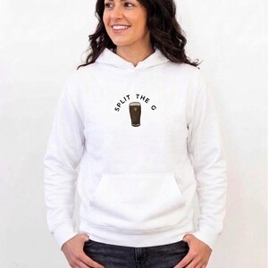 May include: White hoodie with a front pocket and the text "SPLIT THE G" above a graphic of a pint of stout. The hoodie is worn by a person with dark hair and is paired with dark jeans.