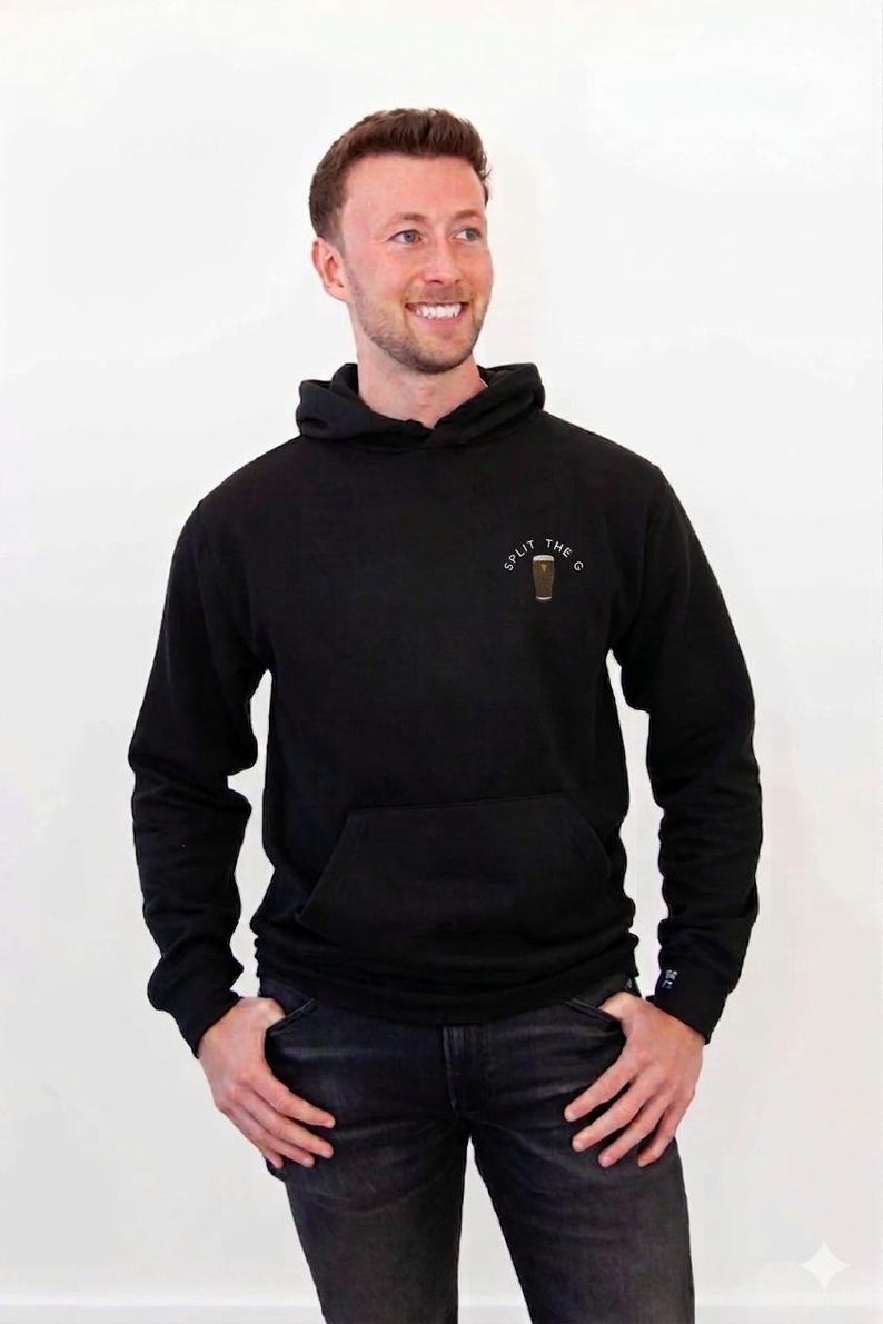 May include: Black hoodie with a front pocket and a hood. The hoodie has the text "SPLIT THE G" and a graphic of a pint glass. The person in the image is wearing black jeans.