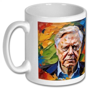 May include: White ceramic coffee mug with a colorful abstract painting of a man's face. The painting features shades of blue, green, yellow, orange, and red.