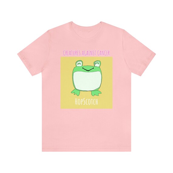 Creatures Against Cancer graphic T-shirt

Design Details:
This is Hopscotch. He is very unfrogettable. He loves to Jump around singing songs and making up new games on his lilypad. His best friend Ribbit loves coming over to sing karaoke. Afterwards, Hopscotch swims around in the water, usually playing Marco Polo with other frogs before heading to bed and thinking about the next day of fun.

Our Mission:
To bring happiness, peace and comfort to cancer patients and survivors. All proceeds go to benefit people living with cancer. We are a 501(c)(3) non-profit, EIN: 81-2224679.

T-Shirt Details:
This classic unisex jersey short sleeve tee fits like a well-loved favorite. These t-shirts have-ribbed knit collars to bolster shaping. The shoulders have taping for better fit over time. Dual side seams hold the garment&#39;s shape for longer. 
.: 100% Airlume combed and ringspun cotton (fiber content may vary for different colors)
.: Light fabric (4.2 oz/yd² (142 g/m²))
.: Retail fit
.: Tear away label
.: Runs true to size