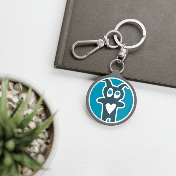 CAC Creature logo keyring. Made with high-quality hardware fittings, a TPU cover, and a robust acrylic plate, this keyring is as durable as it is stylish. Attach this CAC key ring to any keyset like a charm or onto a bag as a tag to help your items stand out in the crowd. Let everyone know you support cancer patients where ever you are.

.: Material: acrylic plate with TPU cover
.: Quality hardware fitting
.: Round shape
.: Key ring included
