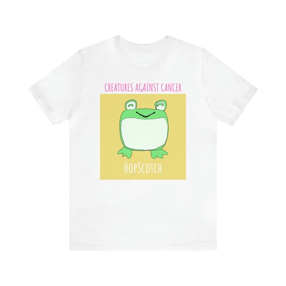 Creatures Against Cancer graphic T-shirt

Design Details:
This is Hopscotch. He is very unfrogettable. He loves to Jump around singing songs and making up new games on his lilypad. His best friend Ribbit loves coming over to sing karaoke. Afterwards, Hopscotch swims around in the water, usually playing Marco Polo with other frogs before heading to bed and thinking about the next day of fun.

Our Mission:
To bring happiness, peace and comfort to cancer patients and survivors. All proceeds go to benefit people living with cancer. We are a 501(c)(3) non-profit, EIN: 81-2224679.

T-Shirt Details:
This classic unisex jersey short sleeve tee fits like a well-loved favorite. These t-shirts have-ribbed knit collars to bolster shaping. The shoulders have taping for better fit over time. Dual side seams hold the garment&#39;s shape for longer. 
.: 100% Airlume combed and ringspun cotton (fiber content may vary for different colors)
.: Light fabric (4.2 oz/yd² (142 g/m²))
.: Retail fit
.: Tear away label
.: Runs true to size