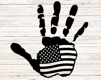 May include: A black handprint with the American flag design inside. The handprint is on a white wood background.