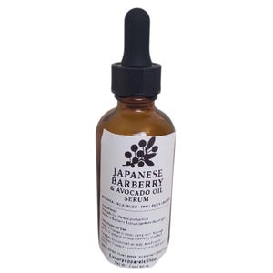 Puede incluir: Una botella de vidrio marrón de suero de Japanese Barberry & Avocado Oil con un cuentagotas negro. La etiqueta presenta texto y una ilustración botánica. La botella contiene 60 ml de suero.
