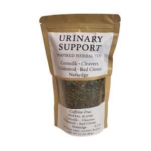 May include: A brown paper bag with a clear window displaying a herbal tea blend. The bag has two white labels with the text "URINARY SUPPORT" and "Caffeine-Free Herbal Blend". The tea blend includes cornsilk, cleavers, goldenrod, red clover, and nutsedge. Net weight is 1.7 oz (48 g).