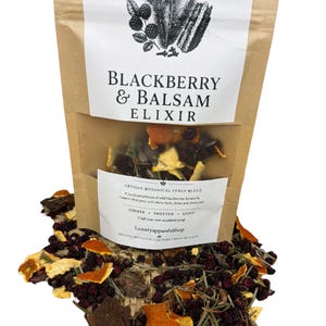 Peut inclure: Un sachet en papier brun étiqueté Blackberry & Balsam Elixir contenant un mélange de sirop botanique. L'étiquette présente une illustration en noir et blanc de baies et d'aiguilles de pin. Des ingrédients séchés dont des écorces d'orange sont visibles.
