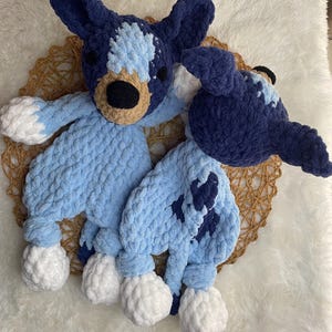 May include: Two crocheted stuffed toys in the shape of dogs. One is blue with white spots and the other is light blue with dark blue spots. Both have white crocheted feet.