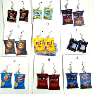 Puede incluir: Un conjunto de nueve pares de pendientes con temática de patatas fritas. Los pendientes están hechos de arcilla polimérica y presentan varias marcas de patatas fritas, incluidas Lay's y Doritos. Los pendientes están disponibles en una variedad de colores, incluidos el azul, el rojo, el morado y el amarillo.