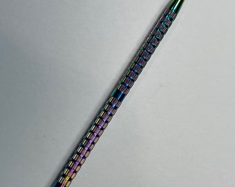 Può includere: Un bastoncino per cuticole in metallo iridescente arcobaleno con una punta appuntita.