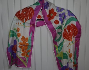May include: A white silk scarf with a pink border and a floral pattern in shades of orange, red, purple, and green.