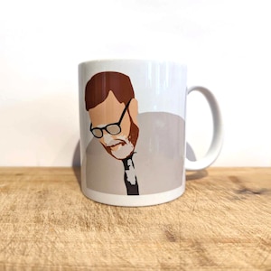 Könnte beinhalten: Weiße Keramiktasse mit einem Motiv eines Mannes mit Brille und einem hellbraunen Hemd und einer Krawatte.