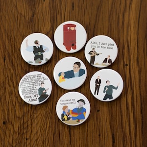 May include: Set of 8 round white button badges with various illustrations and text. The badges feature a red post box, a man with a yellow rubber duck, a man with a guitar, a man with a pie, a man with a microphone, a man with a quote about Alex, a man with a quote about Alex, and a man with a quote about Alex.