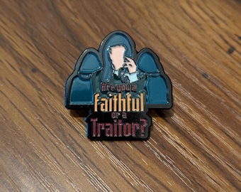 May include: A rectangular enamel pin with a dark teal border and a design featuring a figure with a light skin tone and a dark teal hooded cloak. The text reads "Are you a faithful or a Traitor?"