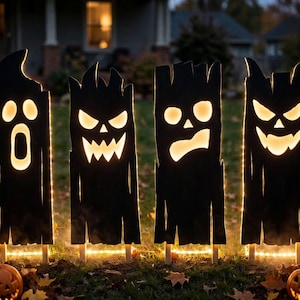 May include: Four black wooden vertical panels featuring cut-out facial expressions illuminated from behind with warm white light. Each panel displays a unique carved face, including a ghost, a jagged-toothed monster, a surprised face, and a grin.