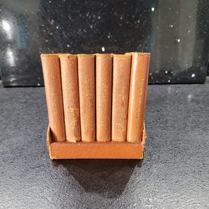 Puede incluir: Un conjunto de seis libros en miniatura encuadernados en cuero con títulos en inglés, francés, alemán, italiano, latín y español.