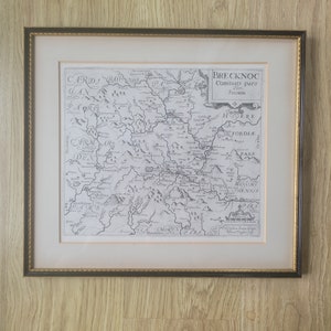 May include: A black and white antique map of Brecknock, a county in Wales, with the text "BRECKNOC Comitaus pars Olim SILARIM" at the top. The map shows the surrounding counties, including Cardiganshire, Radnorshire, Herefordshire, and Monmouthshire.