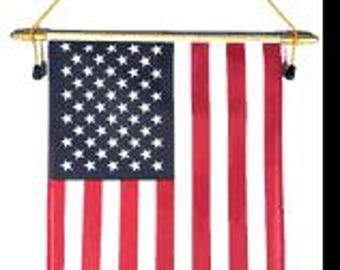 Pode incluir: Uma bandeira americana vertical retangular com listras vermelhas e brancas e um campo azul com estrelas brancas. A bandeira é suspensa por uma barra dourada com um cordão dourado. O fundo é branco.