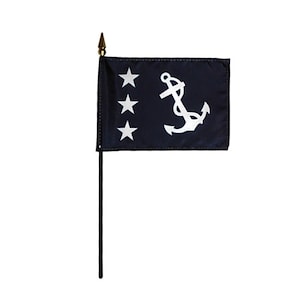 Könnte beinhalten: Eine kleine marineblaue Flagge mit drei weißen Sternen und einem weißen Anker-Emblem. Die Flagge ist an einer schwarzen Stange mit einer goldfarbenen Speerspitze befestigt. Die Flagge ist wahrscheinlich ein nautisches oder maritimes Dekorationsartikel.