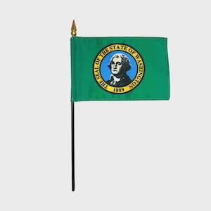 Könnte beinhalten: Eine kleine grüne Flagge mit einem goldenen Siegel, das das Porträt eines Mannes und den Text "The Seal of the State of Washington 1889" zeigt.