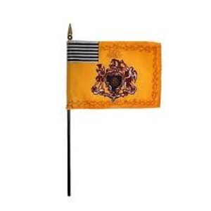 May include: A small, rectangular flag with a black pole. The flag features a gold background with a detailed emblem and border. The upper left corner has horizontal black and gray stripes.