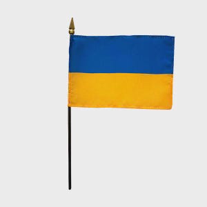 May include: A small desk flag of Ukraine. The flag is blue and yellow with a gold spear-shaped finial on top of the pole.