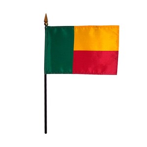 Puede incluir: Una pequeña bandera de Benín en un palo negro. La bandera presenta una franja vertical verde a la izquierda, con franjas horizontales amarillas y rojas a la derecha. El palo tiene una punta dorada.