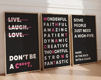 Op de afbeelding: Drie rechthoekige wandposters in licht houten lijsten met zwarte achtergronden en witte tekst. De eerste poster toont LIVE, LAUGH, LOVE met roze doorhalingen en DON'T BE A C***T. De tweede somt bijvoeglijke naamwoorden op die WHAT A C***T spellen. De derde zegt SOME PEOPLE JUST NEED A HIGH-FIVE. HARD. IN THE FACE. WITH A CHAIR.