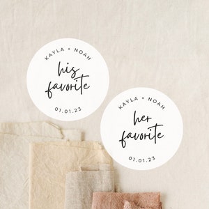 May include: Two white round stickers with black text. The top sticker says "KAYLA + NOAH his favorite 01.01.23". The bottom sticker says "KAYLA + NOAH her favorite 01.01.23".