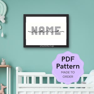 Op de afbeelding: Een ingelijst digitaal kunstprint met het woord "NAME" in gepixelde grijze letters op een witte achtergrond. De print hangt aan een lichtblauwe muur boven een wit wiegje. Een paars label met de tekst "PDF-patroon op bestelling gemaakt" bevindt zich in de rechterbenedenhoek van de afbeelding.