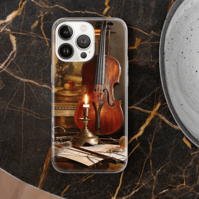 K&ouml;nnte beinhalten: Eine Vintage-Violine mit warmer brauner Oberfl&auml;che steht auf einem Tisch mit einer brennenden Kerze und Noten. Die Violine hat einen dunkelbraunen Holzk&ouml;rper und einen hellbraunen Hals. Die Kerze steht in einem Messing-Kerzenleuchter und die Noten liegen auf einem Tisch mit einer braunen Oberfl&auml;che.