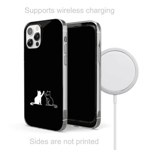 Puede incluir: Una funda de tel&eacute;fono negra con un contorno blanco de dos gatos d&aacute;ndose la mano. La funda es compatible con la carga inal&aacute;mbrica. El texto "Supports wireless charging" est&aacute; en la parte superior de la imagen. El texto "Sides are not printed" est&aacute; en la parte inferior de la imagen.