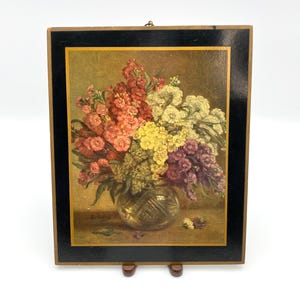 May include: A framed floral print featuring a bouquet of colorful flowers in a glass vase. The flowers include shades of red, pink, yellow, white, and purple. The frame is black with a gold inner border. The print is mounted on a wooden backing.