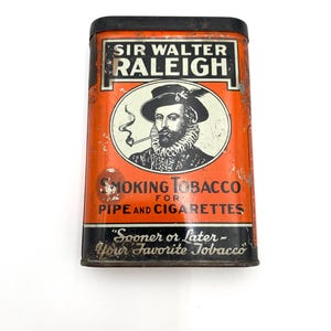 May include: Vintage Sir Walter Raleigh tobacco tin. The rectangular tin features an orange background with black and white text and a portrait of a man smoking a pipe. The text reads "Smoking Tobacco for Pipe and Cigarettes."