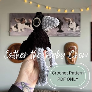May include: A handmade crochet crow plushie with a black body, gray beak and legs, and large white-rimmed eyes. The text "Esther the Baby Crow" is displayed, along with "Crochet Pattern PDF ONLY".