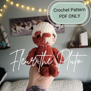 Può includere: Schema di uncinetto PDF per Fleur the Pluto, un giocattolo di peluche all'uncinetto con un corpo rosso e bianco. Il giocattolo è tenuto in una mano con un tatuaggio.