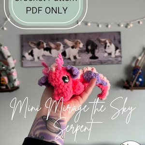 May include: A crochet pattern for a pink and purple mini Mirage the Sky Serpent. The pattern is available as a PDF download only.