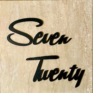 May include: Black metal wall decor with the words "Seven Twenty" in a cursive font.