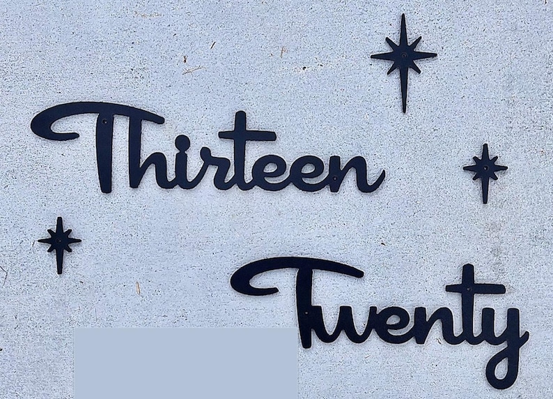 May include: Black metal cutout of the words "Thirteen" and "Twenty" with a star design on a white wall.