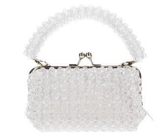 May include: A small, white beaded handbag with a top handle and a gold clasp.