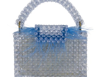 May include: A small, light blue beaded handbag with a top handle. The bag is made of clear plastic beads and has a blue feather trim.
